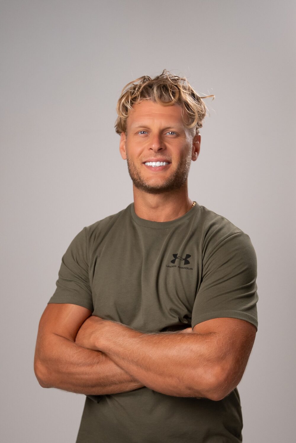 Coach Kyle smiling, arms crossed, in an olive t-shirt